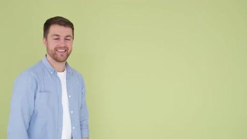 Smiling Attractive Confident Young Man in Blue Shirt Posing on Studio Background