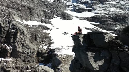 Man sits by himself resting on the mountainside with protective climbing gear. Sitting and enjoying