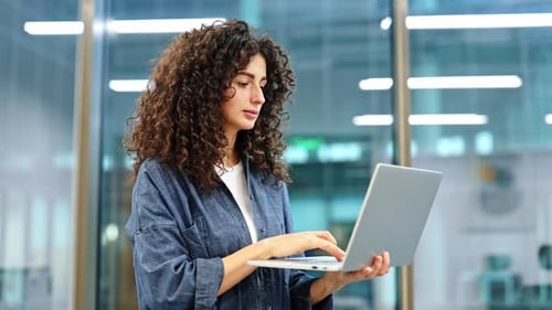 Jeune femme d'affaires utilisant un ordinateur portable dans un bureau moderne, une entrepreneure axée sur un ordinateur