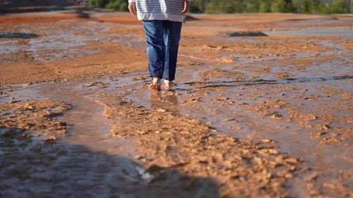 Lone Person Walks Barefoot Across Textured Terrain