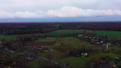 Aerial view of a rural village surrounded by forests and open fields