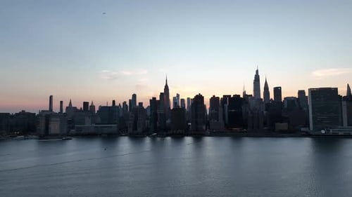 An aerial view of Manhattan from over the East River in NY at sunset. The camera pan left viewing th
