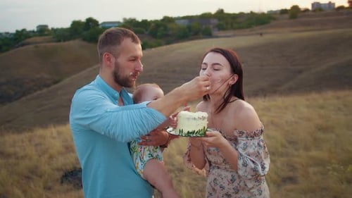 Happy Family with Baby Celebrate First Year Eat Cake in Field at Sunset Autumn and Lifestyle