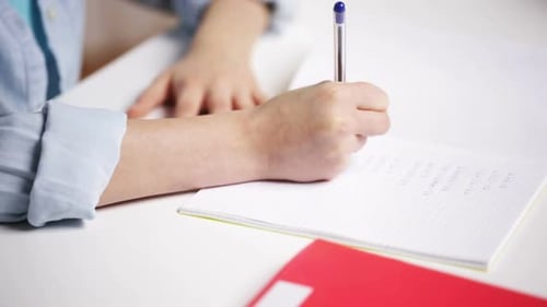 Child Writes Math Problems on Paper at Desk