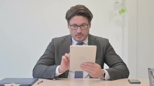 Portrait of Middle Aged Businessman using Digital Tablet in Office
