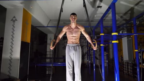 Strong Athlete Doing a Cross on Gymnastic Rings at Modern Gym Muscular Shirtless Sportsman Showing
