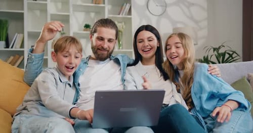 Niños sonrientes, su madre y su padre pasan tiempo juntos divirtiéndose en Internet, usan la computadora portátil.