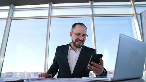 Happy businessman in office on window background.