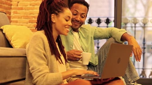 Jovem casal hispânico africano em casa assistindo filme no computador