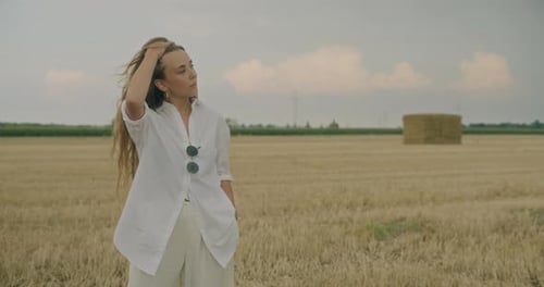 Woman With Hand In Hair Day Dreaming In Field