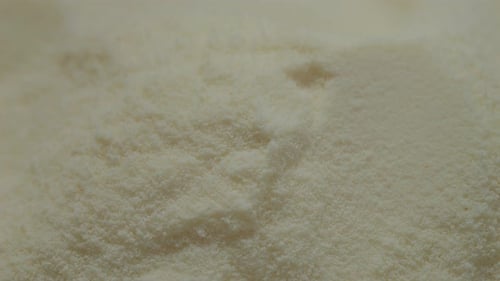 Measuring powdered milk with a spoon for accurate recipe preparation