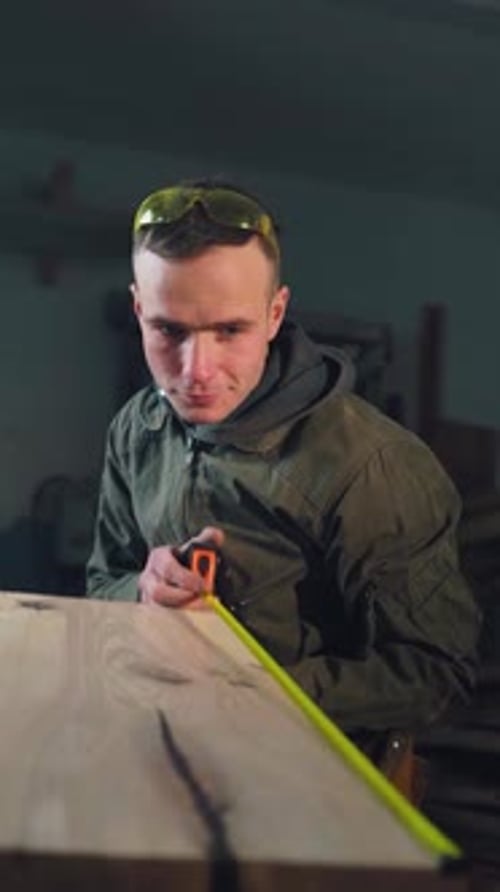 Carpenter Measures Plank of Wood in Workshop
