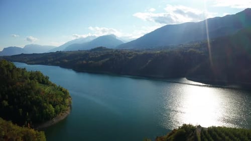 Aerial shot of a scenic panoramic view on a lake with trees in the mountains in a sunny autumn day