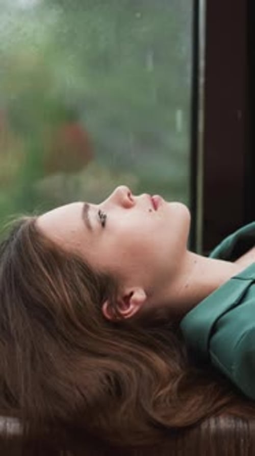 Woman Lying Down by Window During Rain