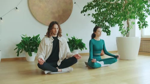 Man and Woman Meditating Together in Bright Room