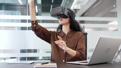 Young businesswoman works using VR glasses in virtual reality simulator while sitting in a business