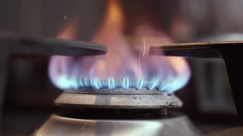 Nahaufnahme des Startens des Gasbrenners zum Kochen des Abendessens, blaue Flammen