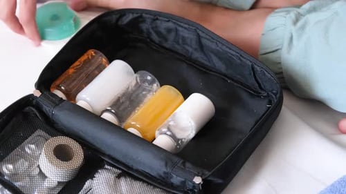 Person Packing Travel Sized Toiletries into Black Bag