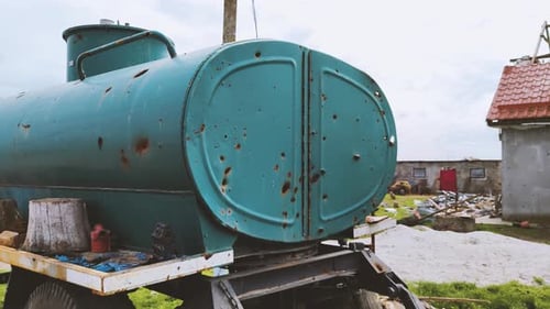 Damaged Water Tank on Trailer in Rural Setting