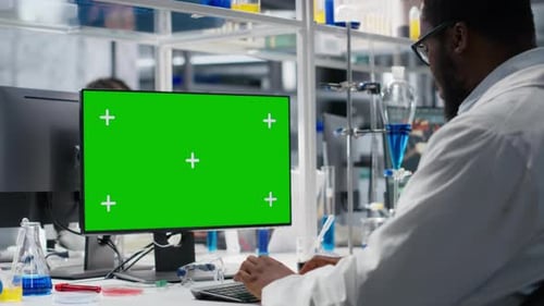 Scientist working on computer with green screen display