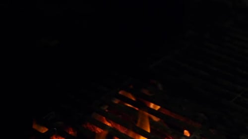 Flammen, die durch einen leeren Grill kommen, gefilmt als Nahaufnahme mit langsamer Schiebebewegung über dem Feuer
