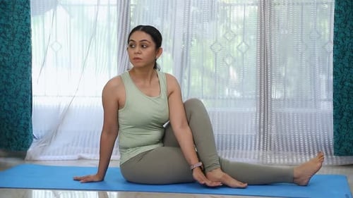 Video of woman performing Vakrasana yoga pose.