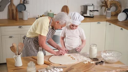 Glückliche Familie in der Küche Großmutter, Enkelin, Kind, schneidet Teigplätzchen auf dem Küchentisch