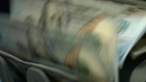 Currency Counting Machine Processing Stacks of United States Dollars