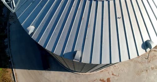 Modern granary at sunlight. Grain elevator. Large silver container for agriproducts. Close-up.