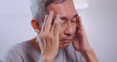 Asian old man with migraine headache. Elderly man suffering from a headache.