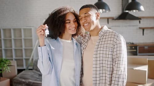 Cheerful Couple with Keys Embraces in New Home