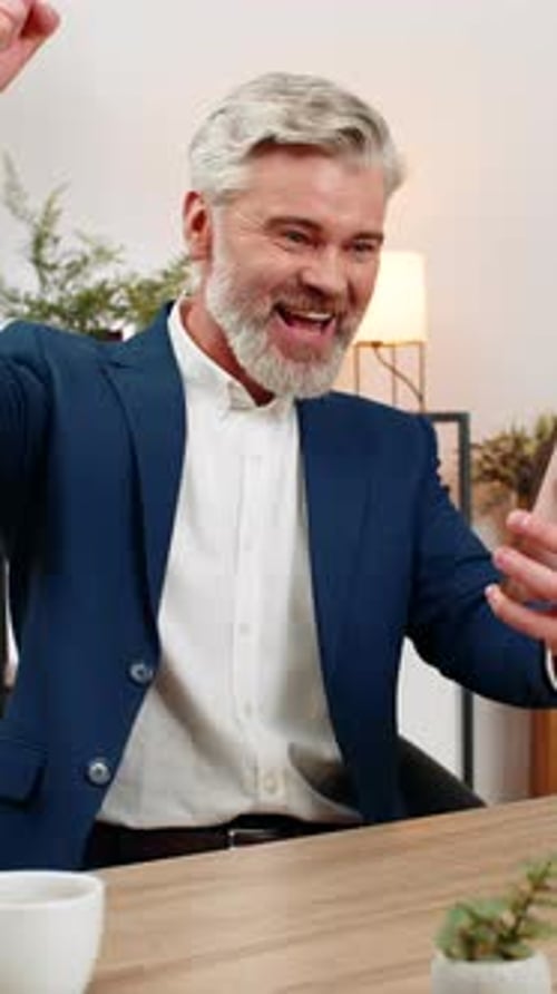 Man Celebrates Good News on His Cellphone Indoors