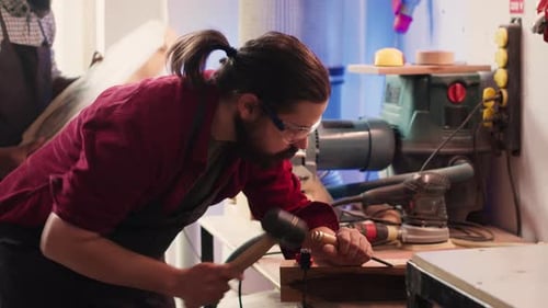 Man Carves Intricate Designs Into Wood Using Chisel and Hammer in Carpentry Shop