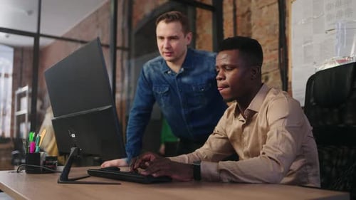 Multiethnisches Team von Büroangestellten arbeitet zusammen Afrikanischer Programmierer korrigiert Code