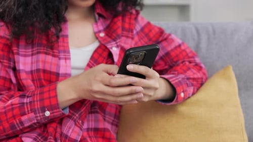 Female Surfing Internet Via Smartphone While Resting on Sofa
