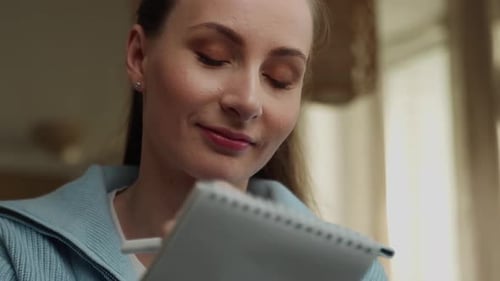 Young Woman Writing in Notebook Indoors