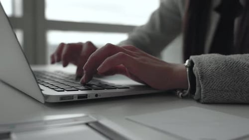 Close up of female hands typing on laptop computer in modern business office