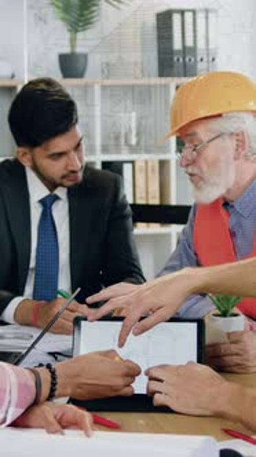 Gut aussehende, verantwortungsbewusste, erfahrene multiethnische männliche und weibliche Architekten sitzen herum und treffen sich.