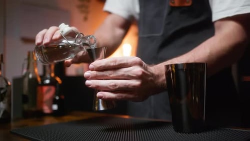Bartender pouring simple syrup into a jigger. Ideal for cocktail-making tutorials, bar promotions, o