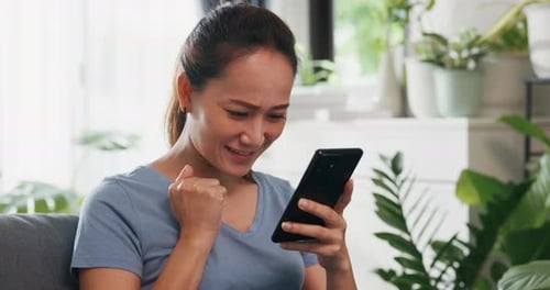 Woman Using Cellphone Smiling Indoors at Home