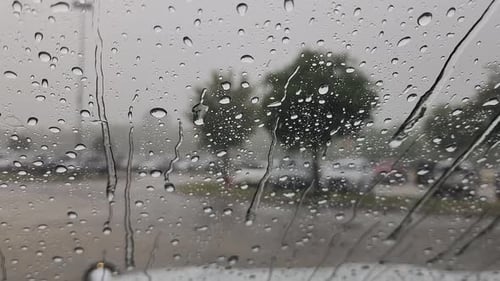 Dies ist ein kurzer Videoclip von Regen, der auf ein Autofenster fällt und große Tröpfchen und kleine Sterne erzeugt
