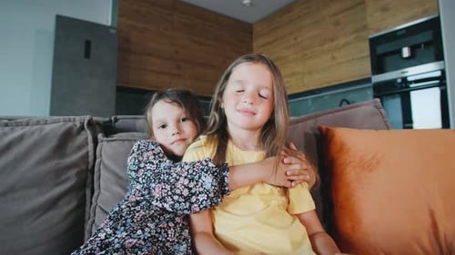 Two Adorable Children Hugging on a Couch Indoors