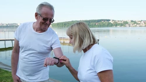 Couple Examining Fitness Tracker By The Lake