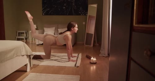 Woman doing yoga in warmly lit bedroom