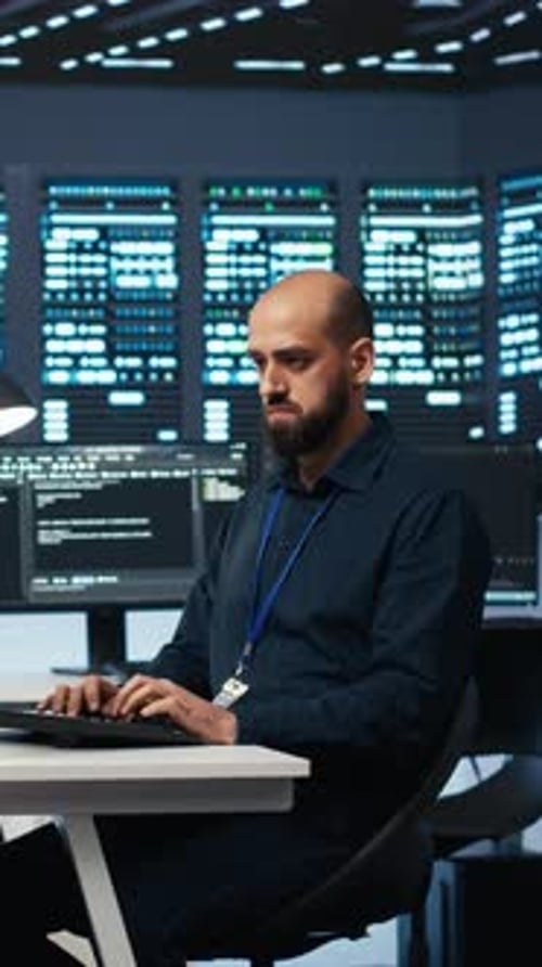 Vertical Video Experienced Person Typing Code on Computer Monitors in Data Center