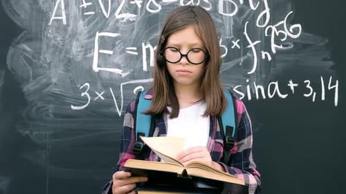 Girl Reading Book in Front of Blackboard
