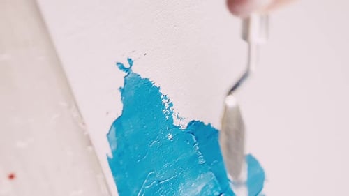Artist Applying Blue Paint with Palette Knife