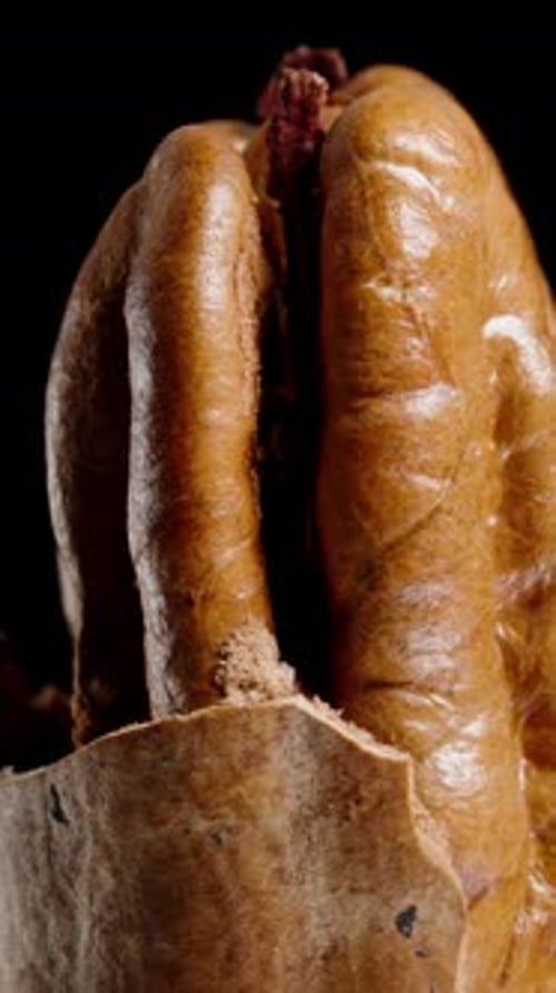 Vertical video. Half-Peeled Pecan Nut Slowly Rotates on a Black Background, Macro.
