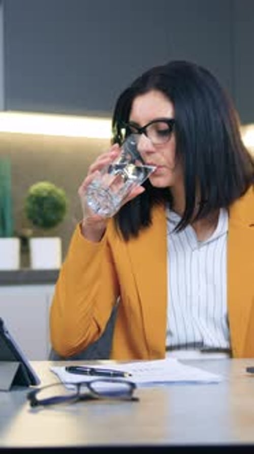 Woman in Blazer Drinking Water While Working