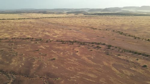 Drone aerial view in Namibia desert flying over red rocky mountains on a sunny day surrounded by
